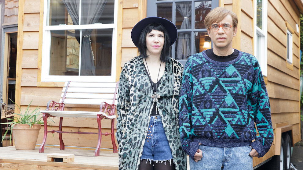 Carrie Brownstein And Fred Armisen From Portlandia Standing In Front Of A Tiny House
