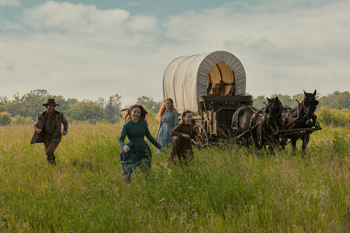 "People run happily with a wagon in the distance. "