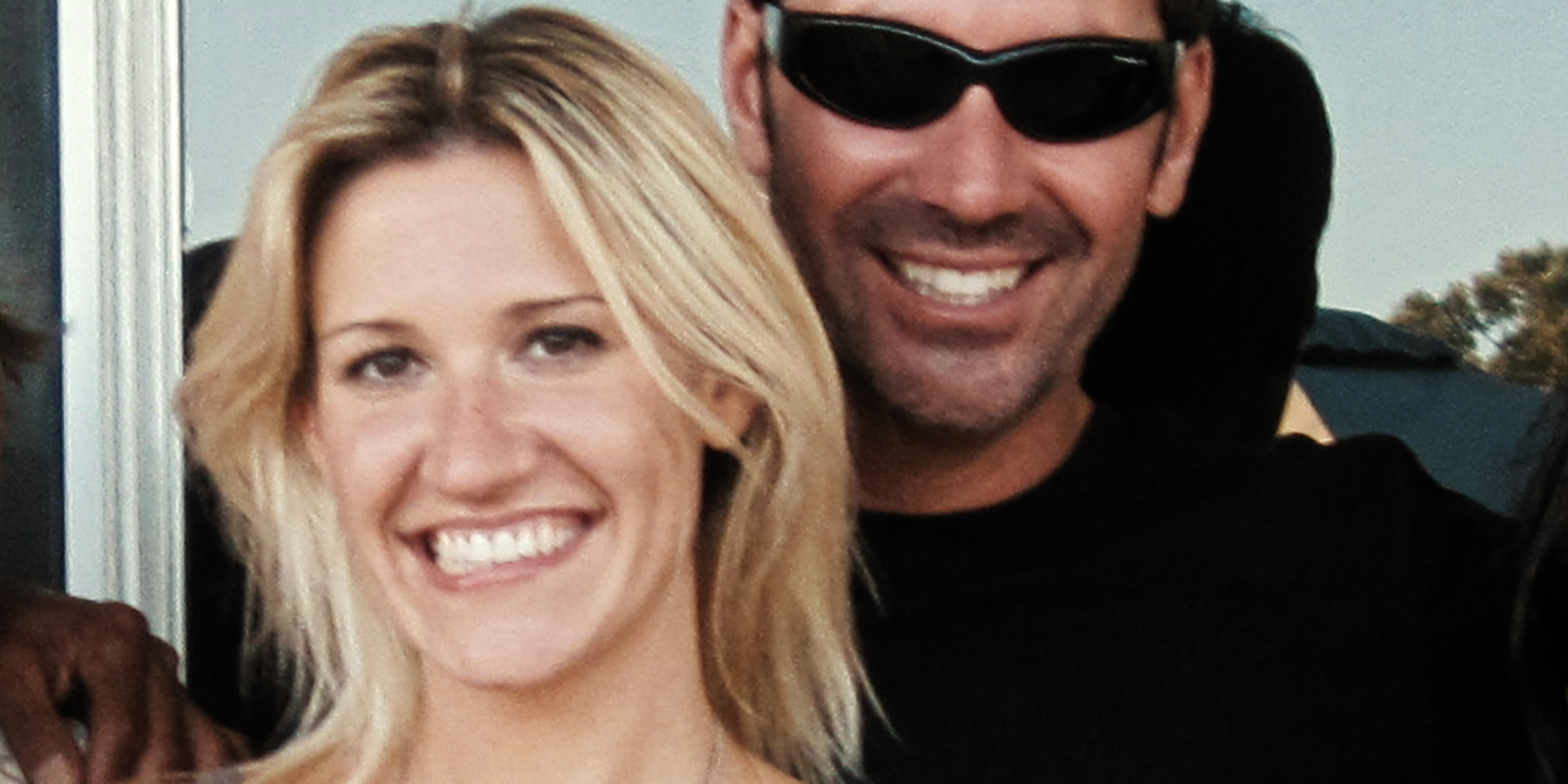 &Quot;Smiling Woman With Blonde Hair And A Man In Sunglasses Standing Close Together Outdoors, Both Appearing Happy With Sunlight And Greenery In The Background.&Quot;