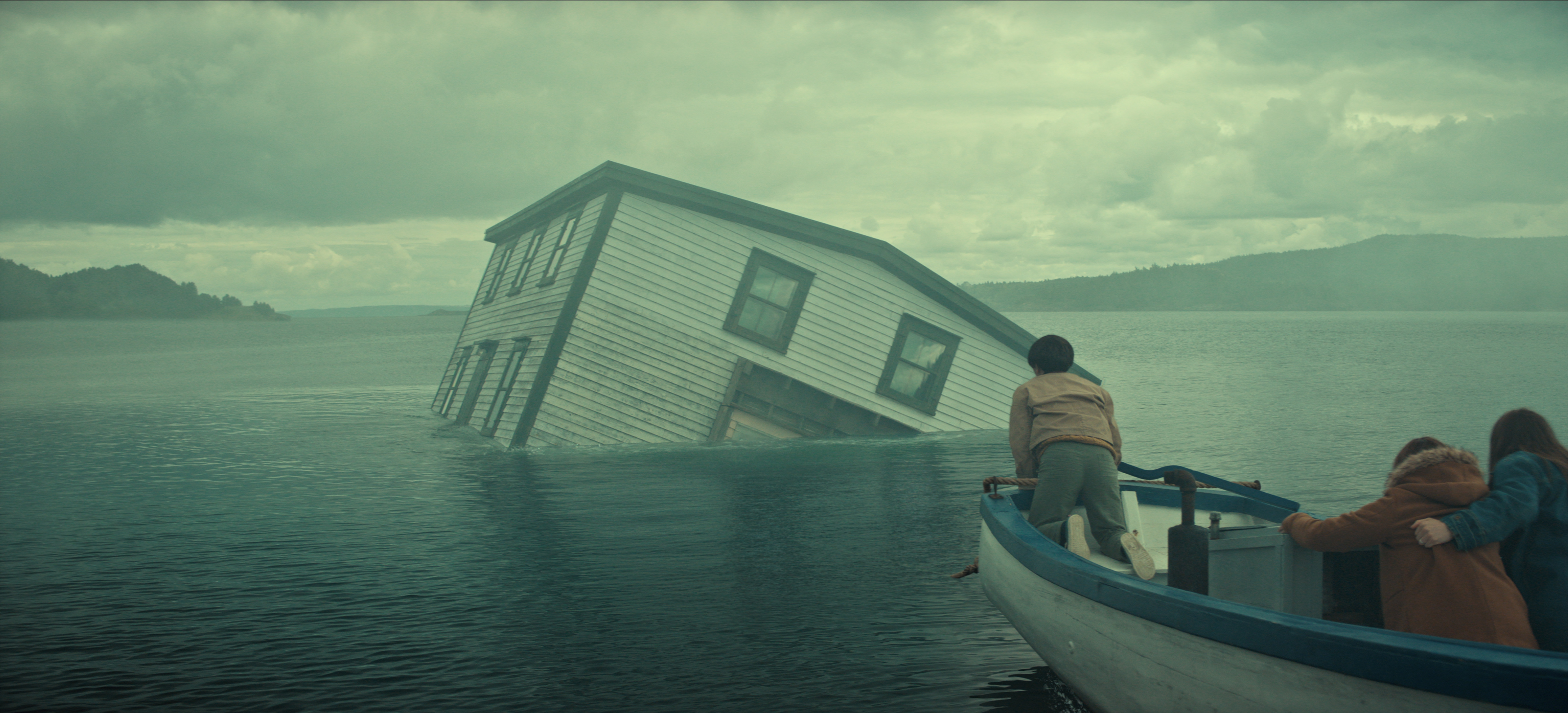 "A partially submerged house tilts in a misty lake as three people in a small boat observe, with cloudy skies and distant hills creating a dramatic, mysterious atmosphere."